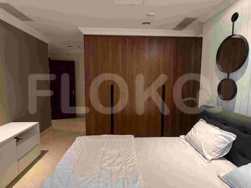 A bedroom with a large wooden wardrobe, a bed, and a side table.