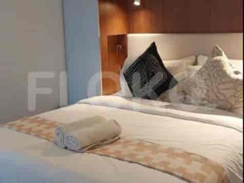 A cozy bedroom featuring a double bed with decorative pillows and rolled towels.