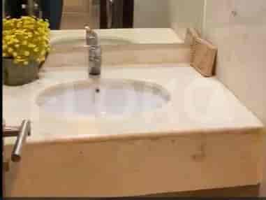 A bathroom with a sink, countertop, and a floral arrangement.