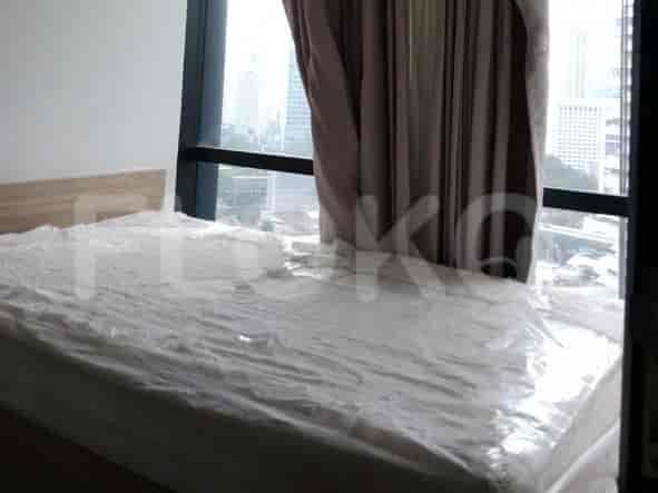 Another view of a bedroom with a bed covered in plastic and large windows.
