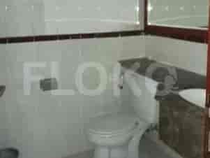A bathroom with a toilet, sink, and tiled walls.