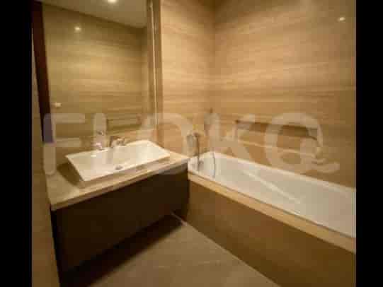 A bathroom with a bathtub, a sink with a vanity, and beige marble walls.