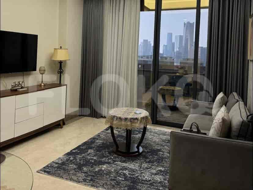 A modern living room with a grey sofa, a coffee table on a rug, and a wall-mounted TV, overlooking a cityscape through a large window.