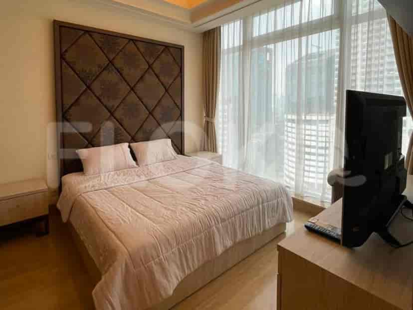 A bedroom with a king-size bed, a large headboard, and a TV.