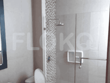 Kamar mandi modern dengan pancuran berkaca, dinding berubin, dan toilet bergaya Barat.
