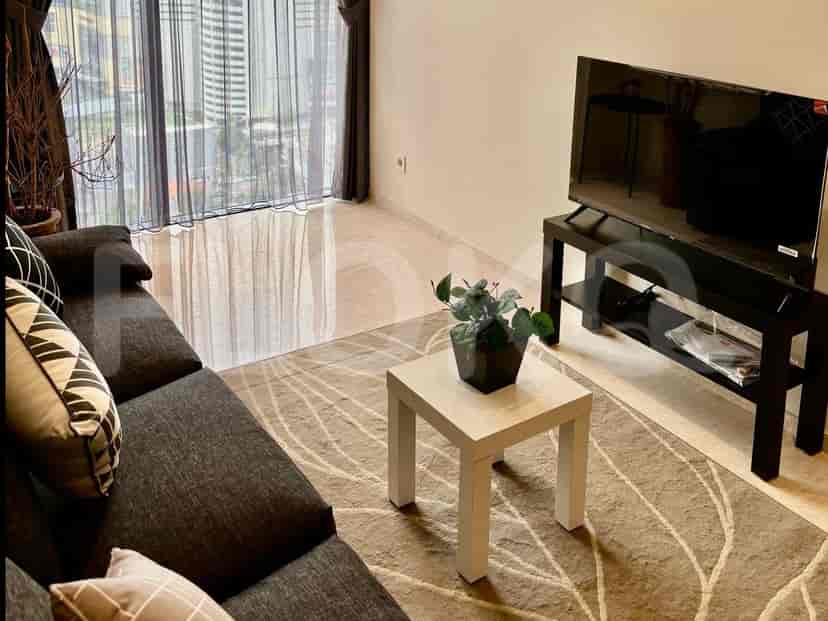 A cozy living room setup with a grey sofa, a coffee table, and a large window with sheer curtains, offering a city view.