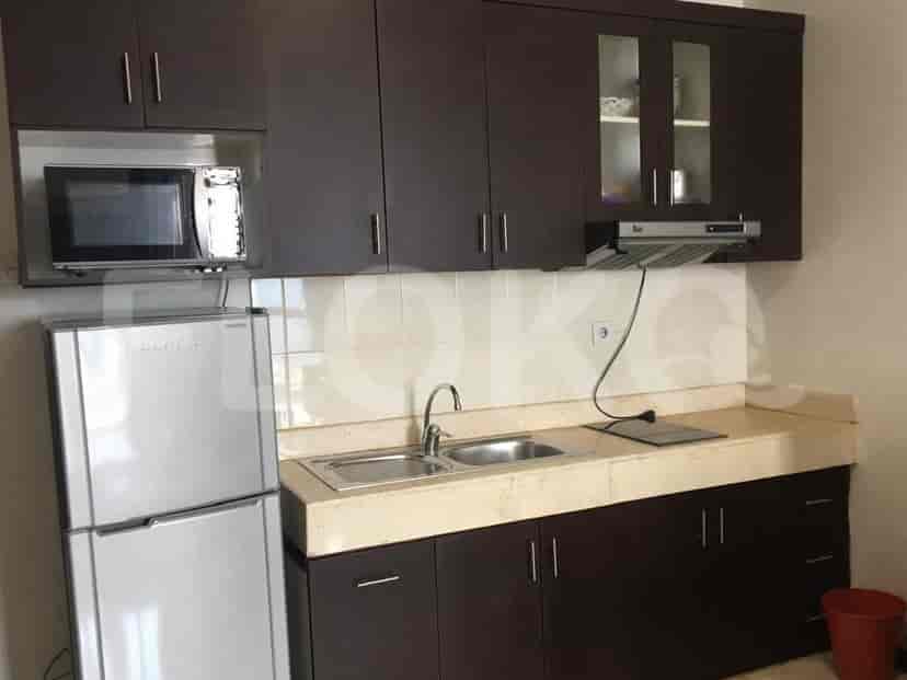 Close-up of the kitchenette showing the refrigerator, microwave, sink, and cabinets.