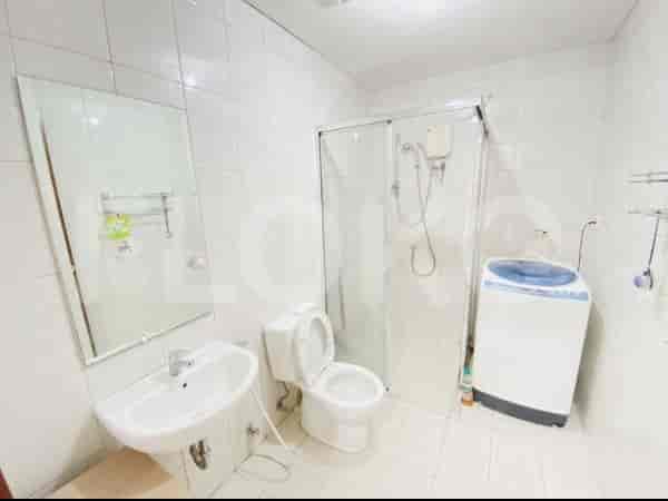 Kamar mandi yang bersih dan cerah dengan penutup pancuran kaca.