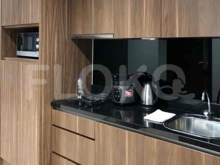 Sebuah dapur kecil yang ringkas dengan lemari kayu, microwave, kompor, dan wastafel.