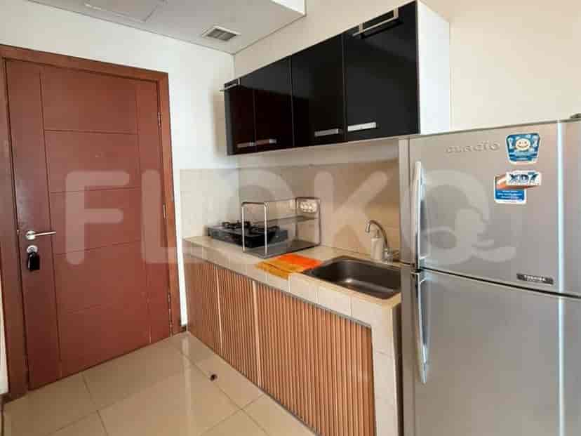 A compact kitchen area with stainless steel refrigerator, gas stove, sink, and cabinets.