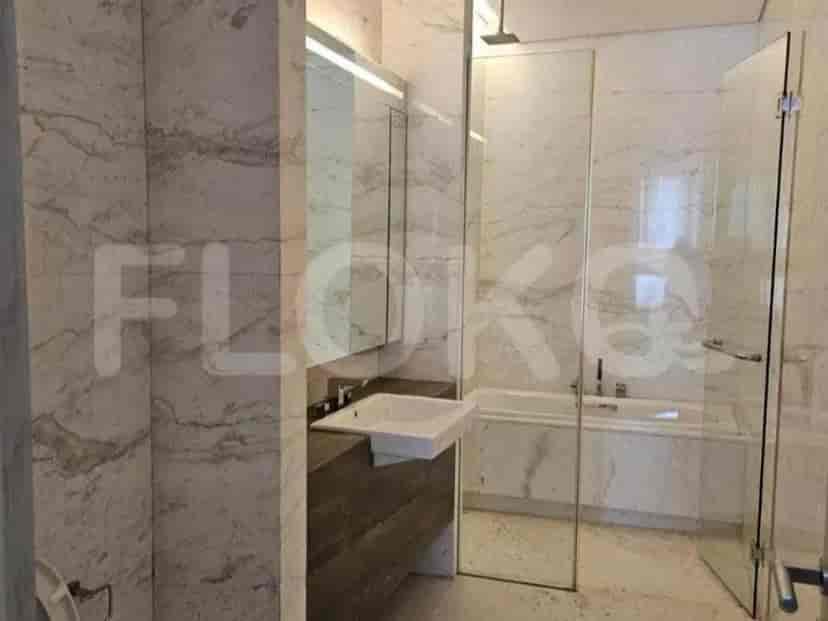 A bathroom with marble walls, a vanity, a sink, and a bathtub with a glass enclosure.