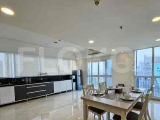 A dining area with a wooden table and chairs, adjacent to a kitchen with modern cabinetry.