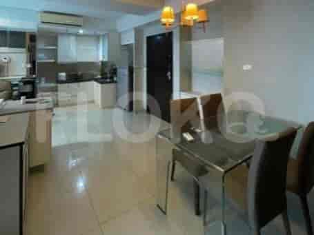Dining area with a glass table and chairs connected to an open kitchen.