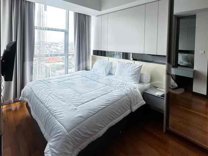 Sebuah kamar tidur luas dengan selimut putih besar di atas tempat tidur, jendela dari lantai ke langit-langit, dan lantai kayu.