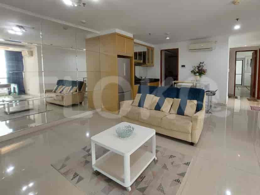 A living room with mirrored walls, a beige sofa with accent pillows, a white coffee table, and a small dining area.