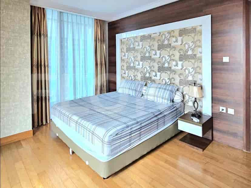 A bedroom with a queen-sized bed, bedside table, and large window with curtains.