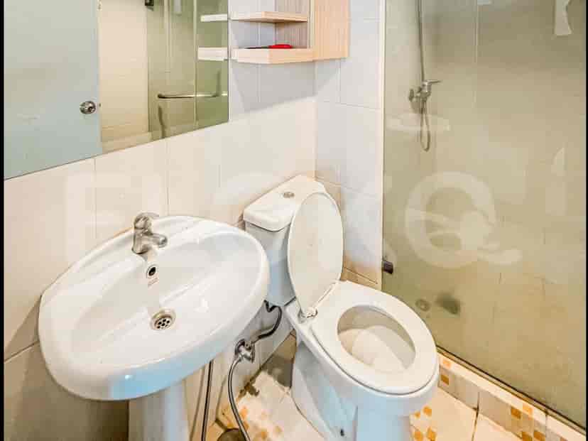 Kamar mandi dengan toilet putih, wastafel, dan pancuran.