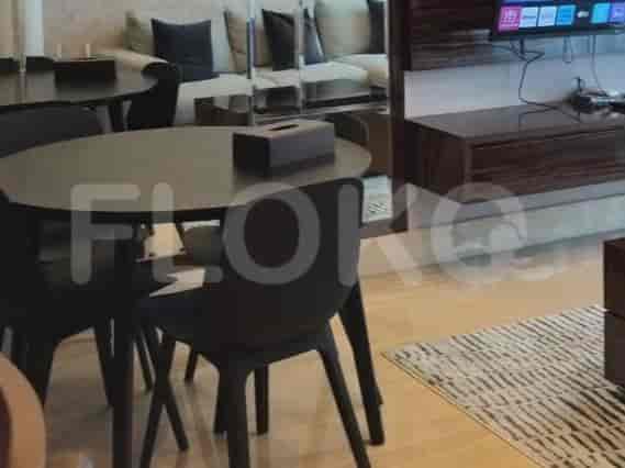 A dining area with a round black table and four chairs, adjacent to a living area with a sofa.