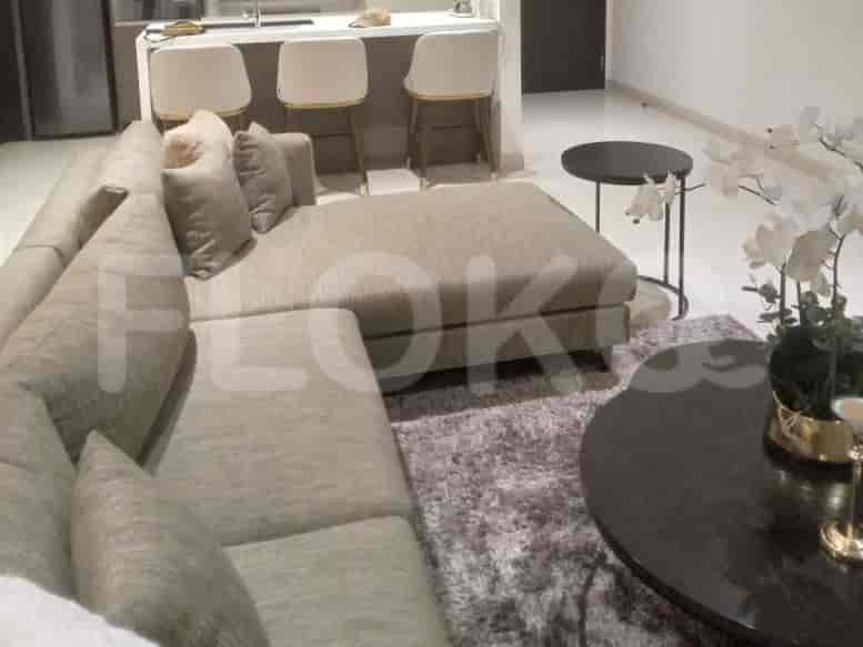 A sectional grey sofa with pillows and a round coffee table with a vase of flowers.