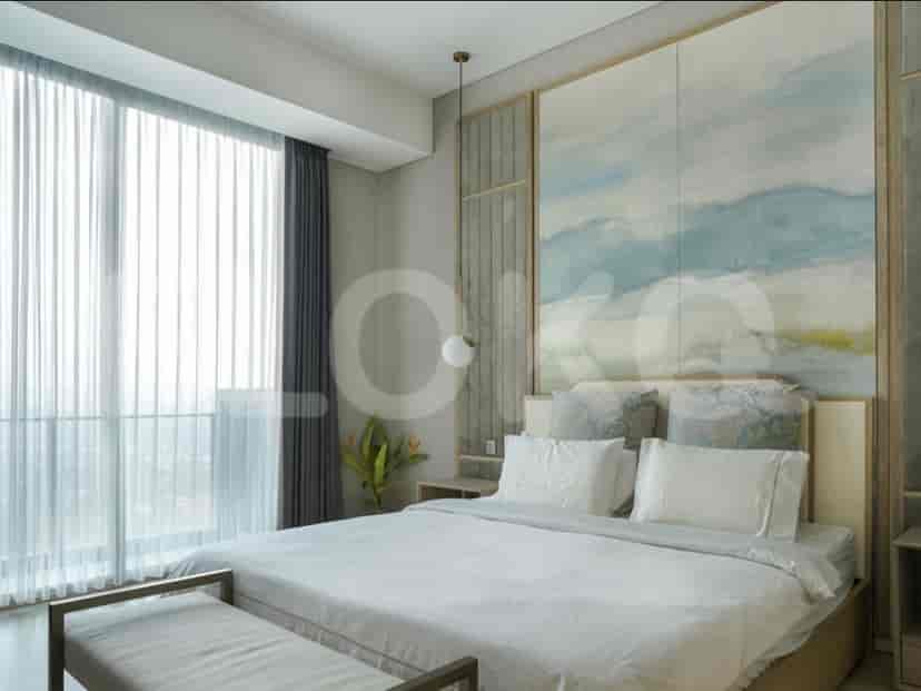 A spacious bedroom with a large bed, decorative headboard, and sheer curtains covering a wide window.