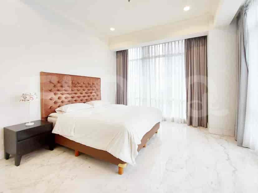 A spacious bedroom featuring a large bed with a tufted headboard, nightstand, and a large window.