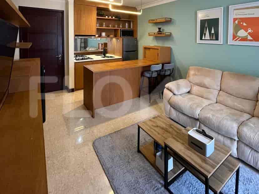 An open-plan living room and kitchen with wooden cabinetry, a breakfast bar, and a light-colored sofa.