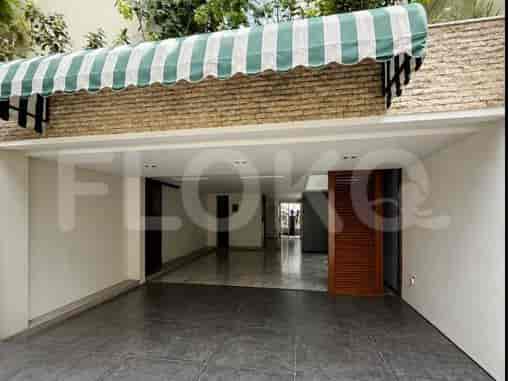 Fasad modern dengan tenda bergaris hijau dan putih di atas jalan masuk dan pintu masuk.