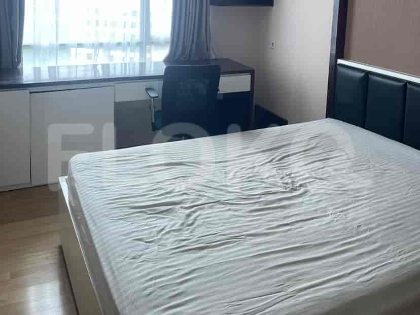 A bedroom with a bed, desk, and chair by a window.
