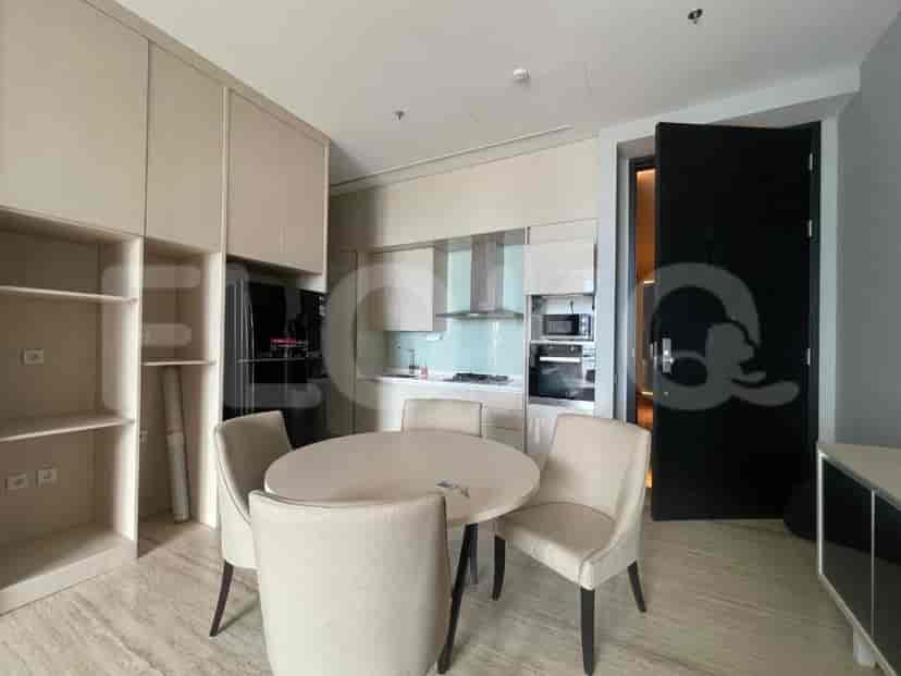 A dining area with a round table and four chairs, adjacent to a kitchen and a large shelving unit.