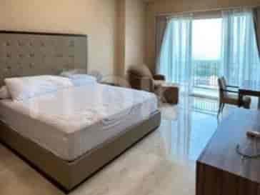 A spacious bedroom with a large bed, a chair, a desk, and a big window.