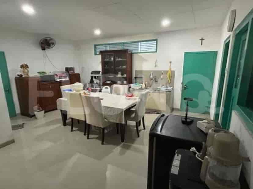 Area makan dengan meja besar dan kursi, bersebelahan dengan meja dapur dan area wastafel.