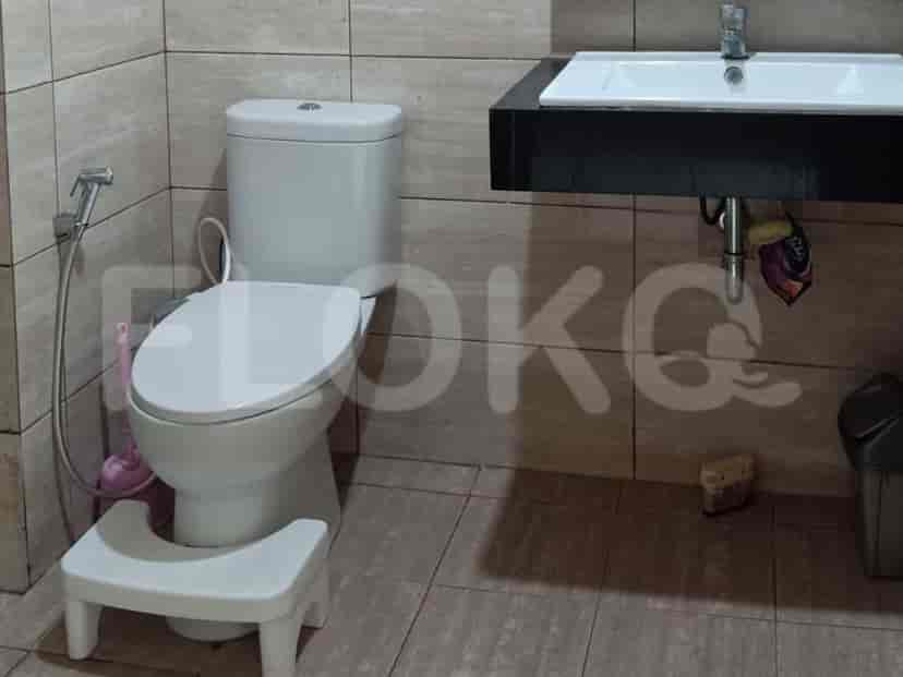 A small bathroom with a toilet, bidet shower, sink, and a small step stool.