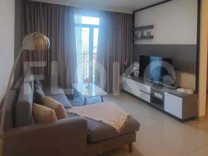 Ruang tamu modern dengan sofa berbentuk sectional, konsol TV, dan jendela besar dengan gorden tipis.