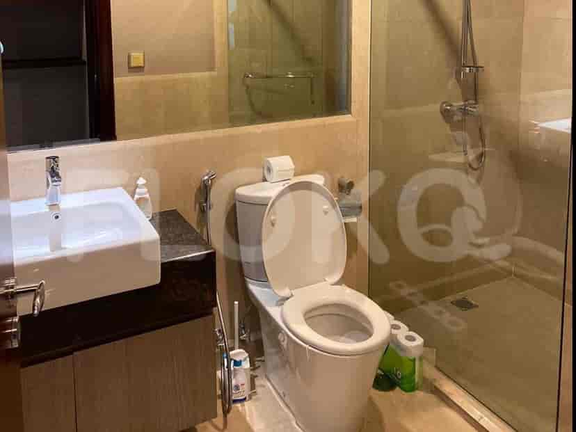 Kamar mandi dengan toilet, wastafel, dan pancuran kaca.
