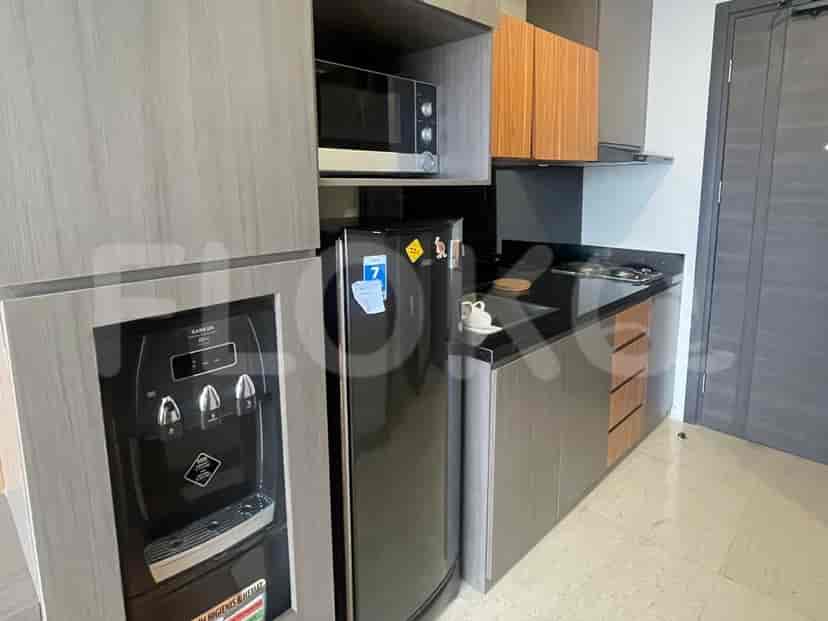 A compact kitchenette with a refrigerator, microwave, water dispenser, and stovetop.