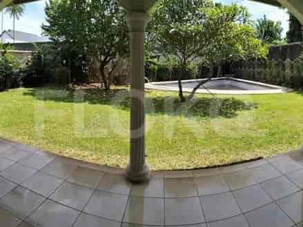 A lush green lawn with a swimming pool and trees, viewed from a covered patio area.