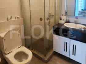 Kamar mandi dengan toilet, bilik shower, dan meja rias dengan wastafel.