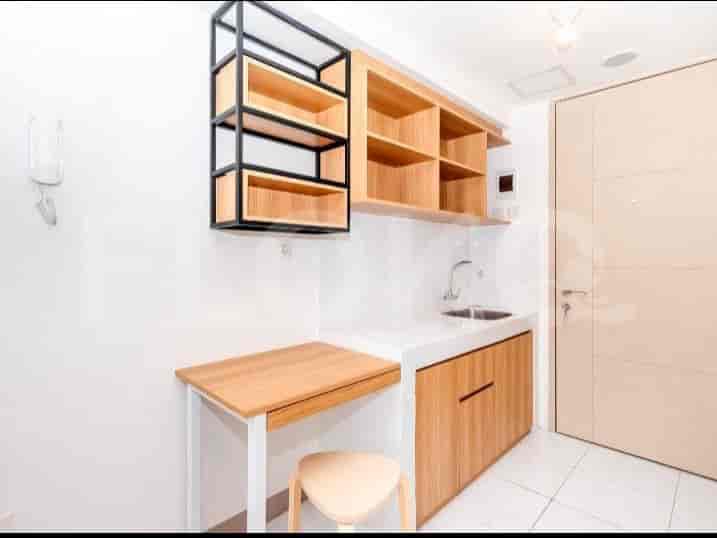 A compact kitchenette with wooden cabinetry, a sink, and a small dining table.