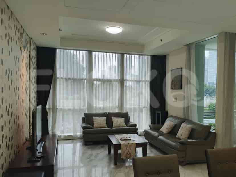 A well-lit living room with two grey sofas, a coffee table, and large windows.
