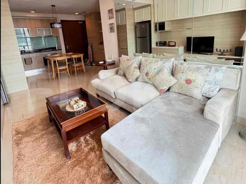 A contemporary living room with a plush L-shaped sofa, a wooden coffee table, and an adjacent dining area visible.