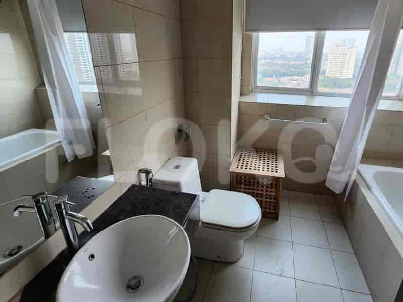 Kamar mandi dengan bak mandi, toilet, wastafel, dan cermin besar, menampilkan dinding berkeramik dan pemandangan kota.
