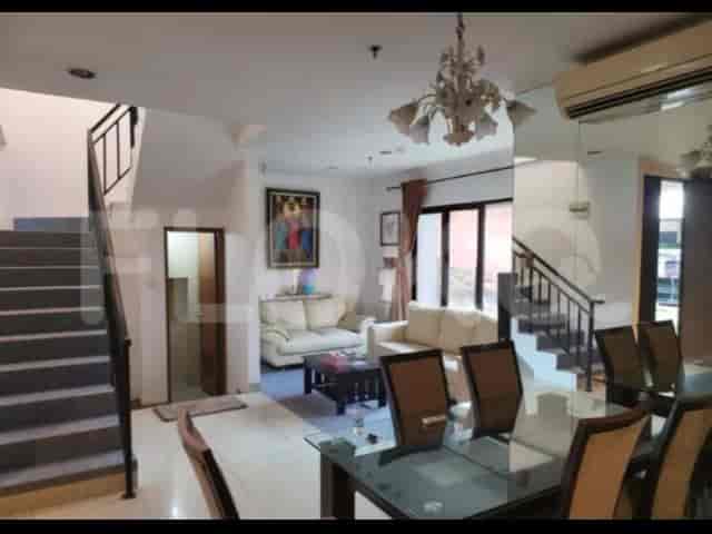 A living room and dining area showing a staircase, sofa, dining table, and chandelier.