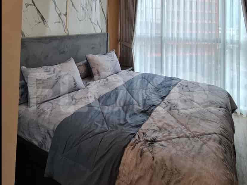 A bedroom featuring a queen-sized bed with a grey upholstered headboard and patterned bedding.