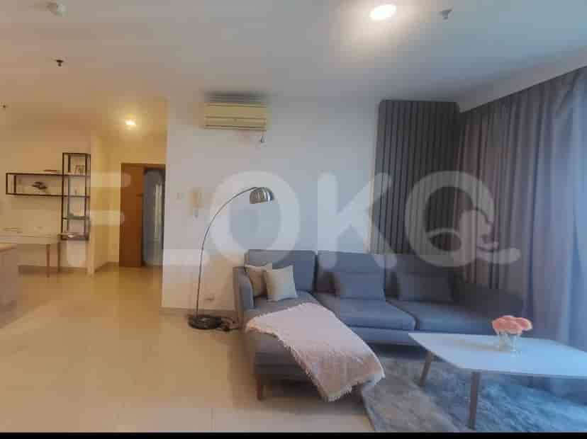 Ruang tamu luas dengan sofa sectional abu-abu, lampu lantai, dan elemen dekoratif.