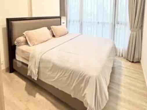 Kamar tidur dengan tempat tidur besar berlapis seprai krem dan kepala ranjang kayu gelap, dengan tirai di latar belakang.
