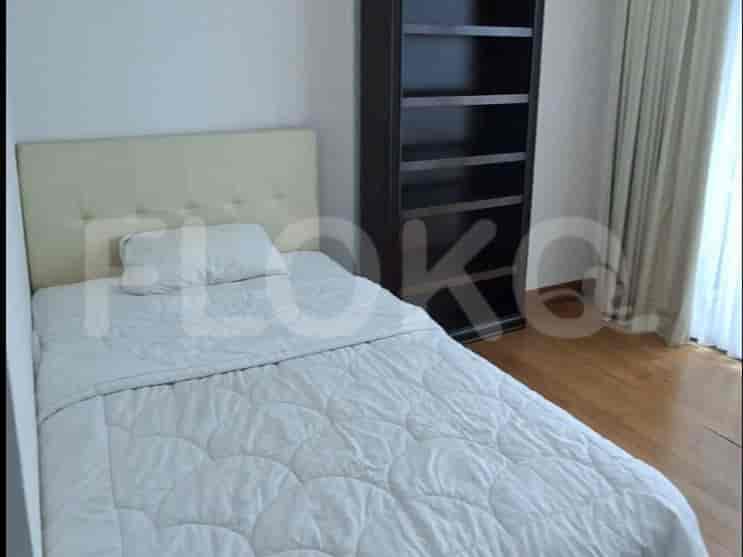 A bedroom with a single bed, a tall bookshelf, and large windows.