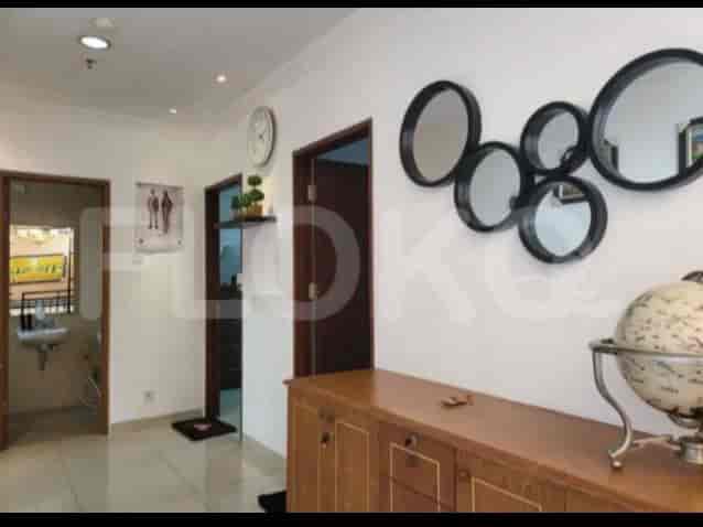 A hallway with a round mirror decor, artwork, a cabinet, and doors leading to other rooms.