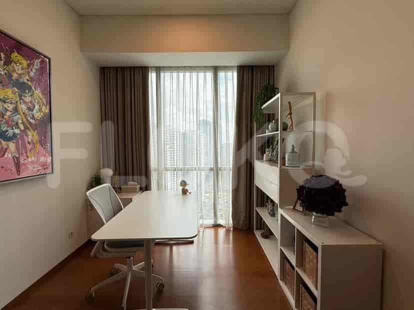 A home office with a desk, shelving unit, and large windows offering a city view.
