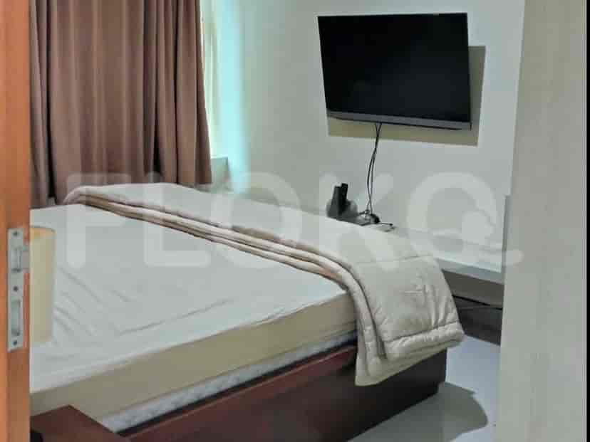 Sebuah kamar tidur yang nyaman dengan tempat tidur ukuran queen, TV yang terpasang di dinding, dan gorden cokelat.