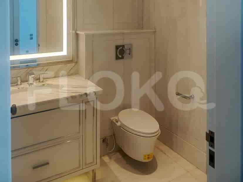 A luxurious bathroom with marble walls and flooring, a vanity with a sink and faucet, and a toilet.